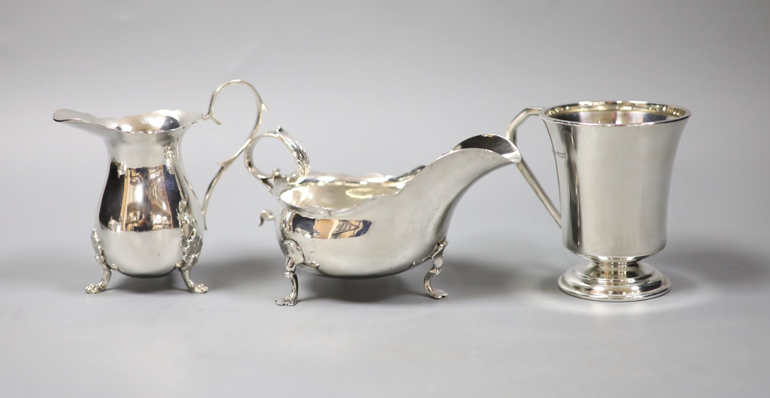 An Edwardian silver sauce boat, London, 1901 and a later silver cream jug and mug, 9oz.